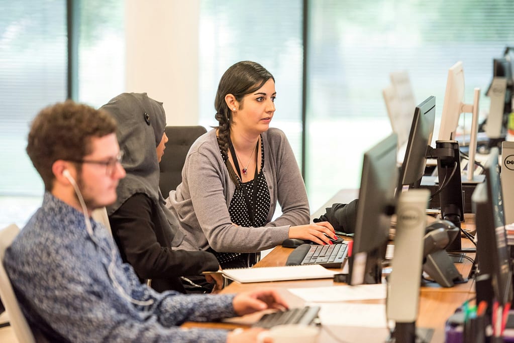 A man and two women working at computers