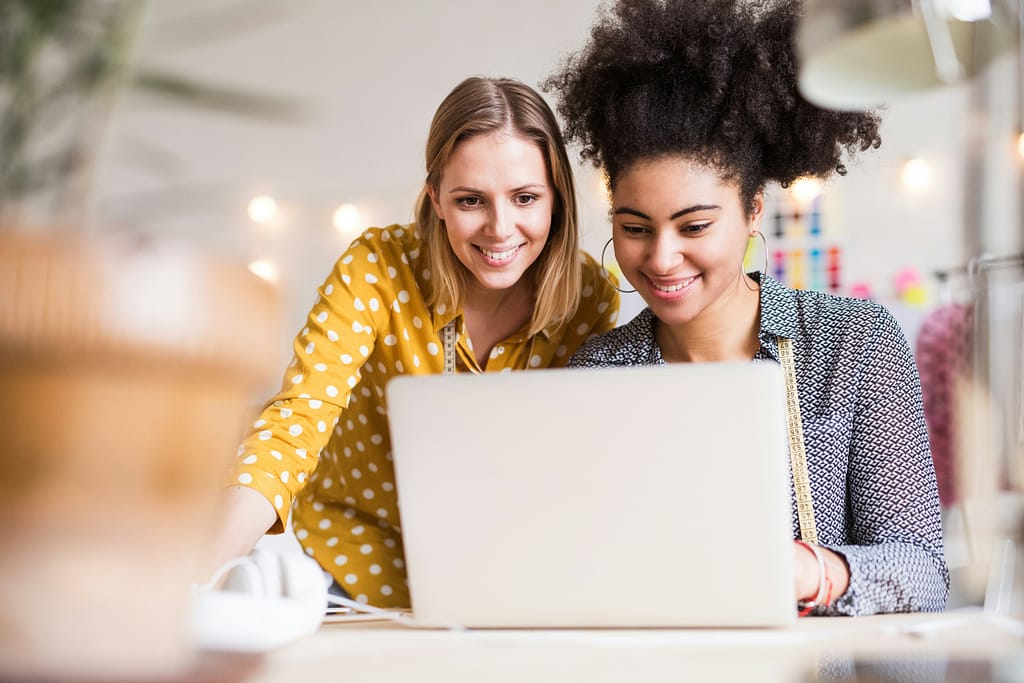 Two young women working on a laptop