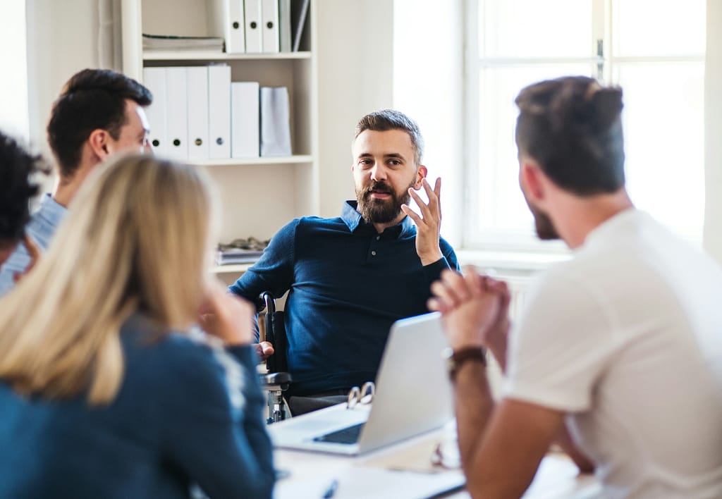 A man talking to four colleagues around a table