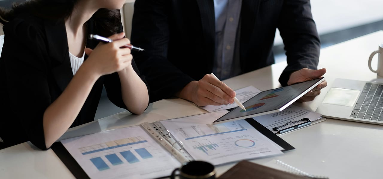Close-up of one colleague showing another a graph on a tablet